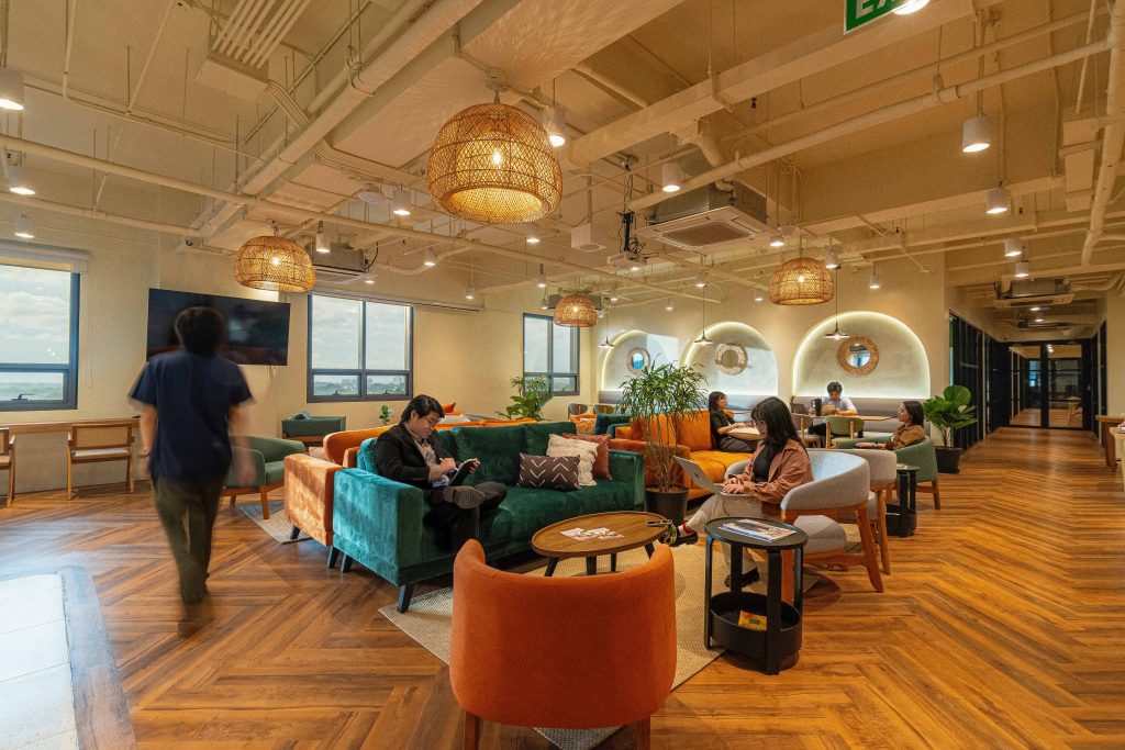 A welcoming common area at Common Ground Don Antonio in Quezon City, featuring colourful lounge seating, wooden flooring and warm pendant lighting.