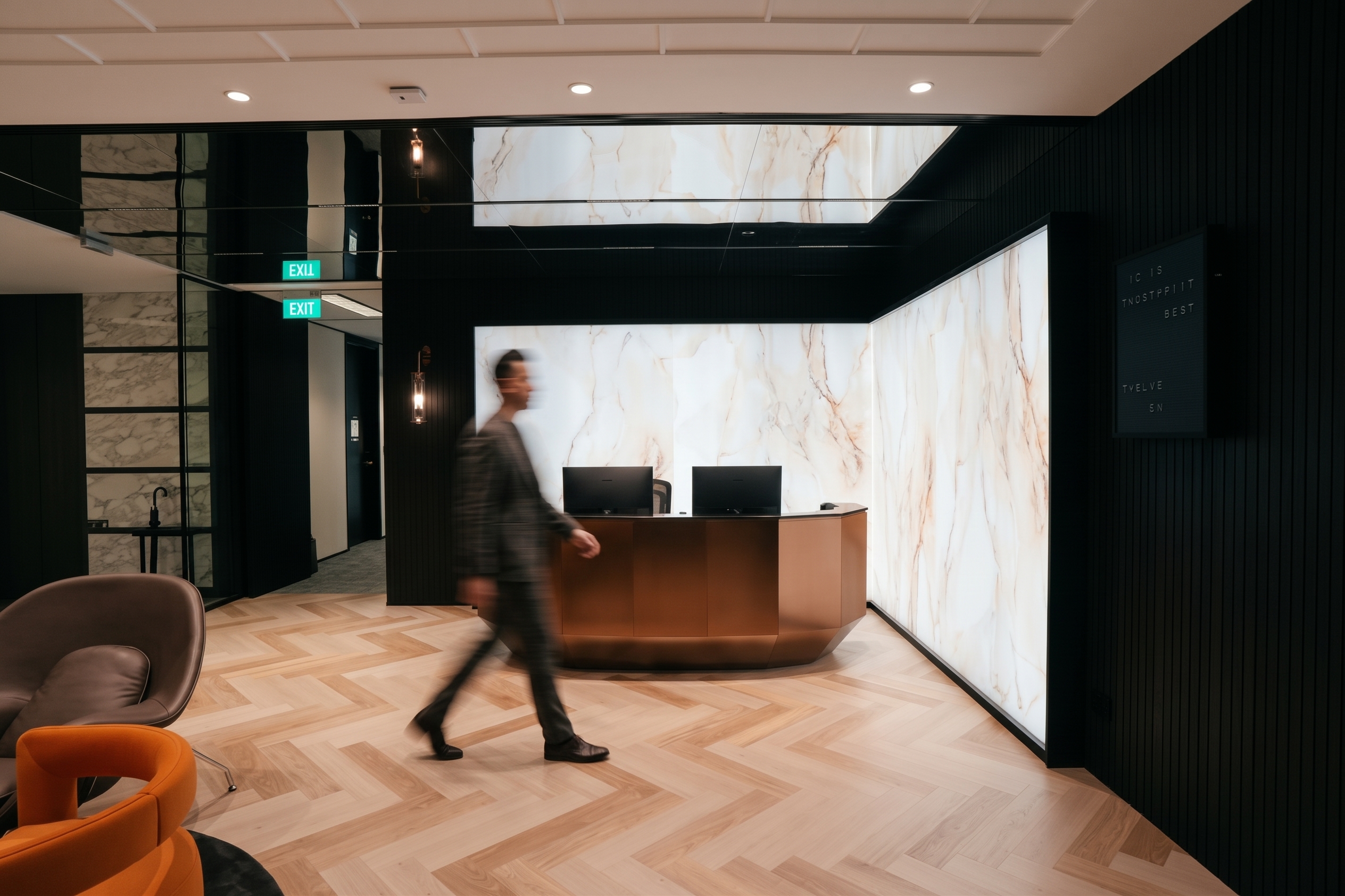 Premium office reception featuring marble wall panels, a bronze reception desk and contemporary interior design.